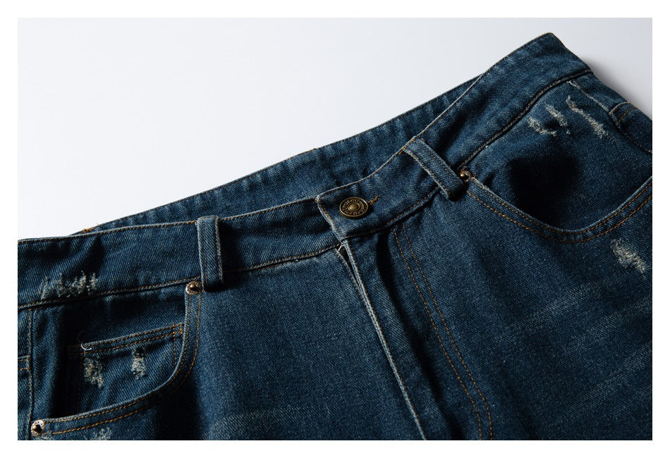 Cropped front view of dark blue distressed jeans showing the waistband, button, belt loops and pockets.