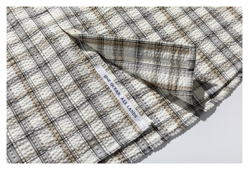 Close-up of the shirt’s inside placket and sewn label reading “ONE OCEAN, ALL LANDS.”