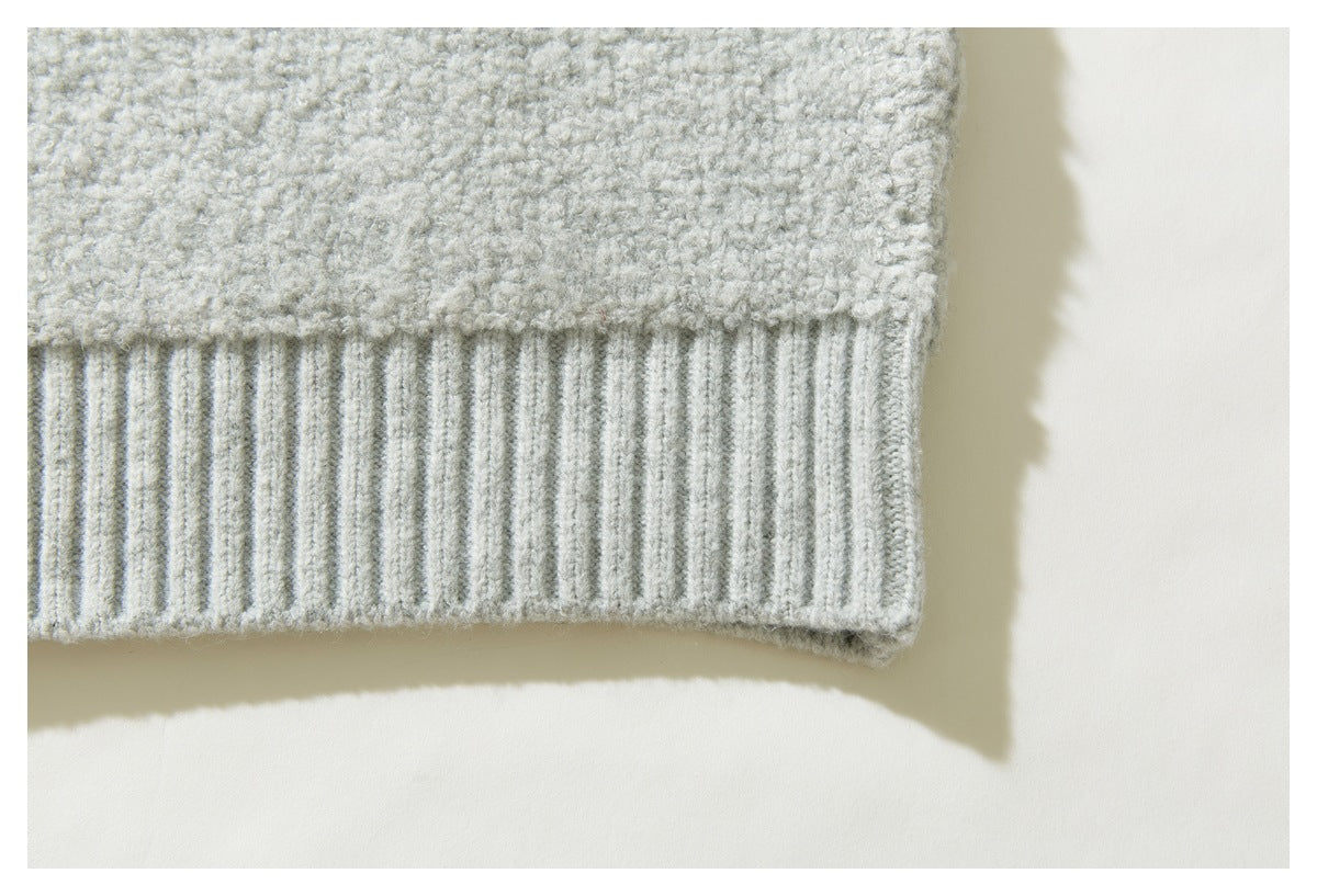 Close-up of the light gray sweater's textured fabric and ribbed hem.