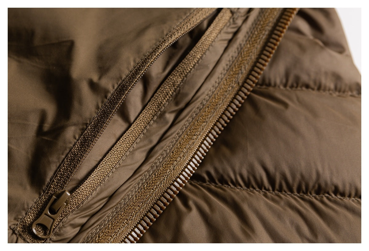 Close-up of a brown padded jacket showing its zipper, zipper pull and quilted fabric.
