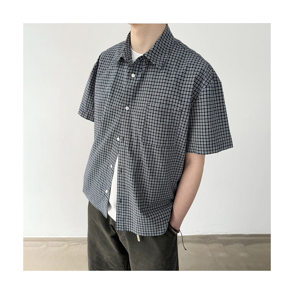 Cropped view of a model wearing a black-and-white checked short-sleeve shirt over a white top.