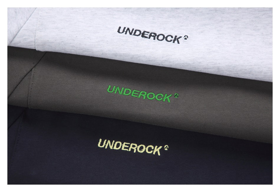 Close-up of white, charcoal gray, and black garments with embroidered UNDEROCK wordmarks.