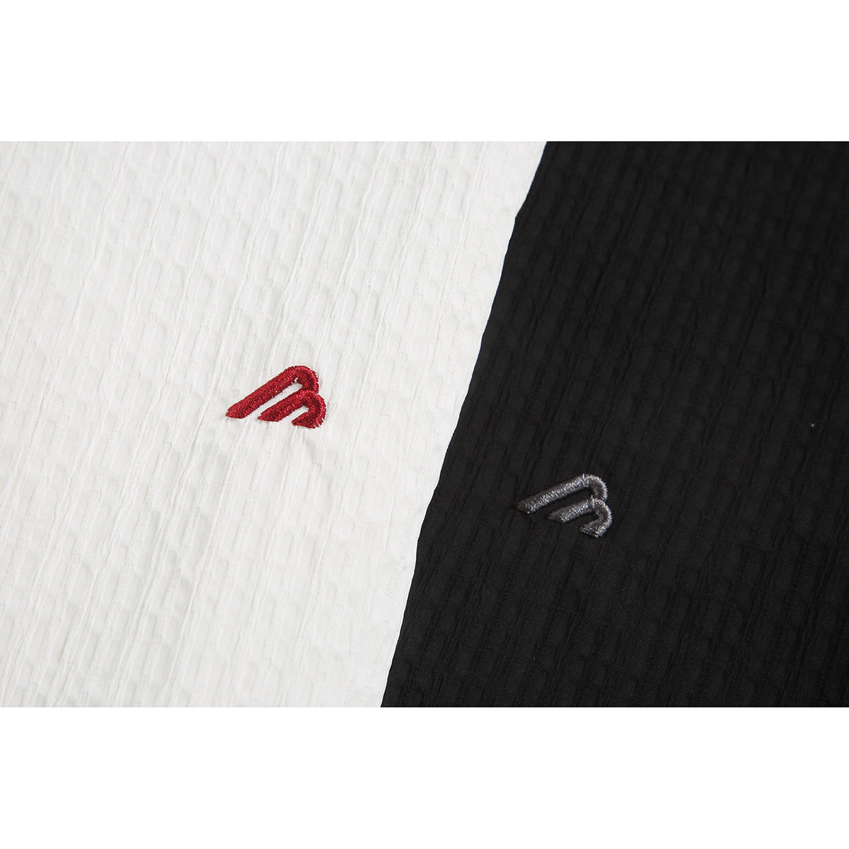 Close-up of red and gray embroidered emblems on white and black textured shirt fabric.