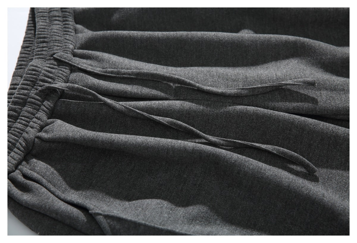 Close-up of dark gray pants showing the waistband and two drawstring ends across the front.