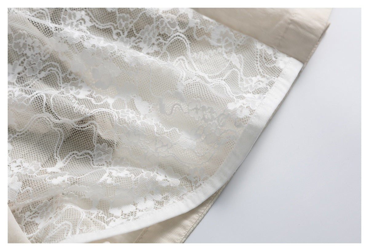 Close-up of a white floral lace panel layered over cream fabric, with a curved stitched edge.