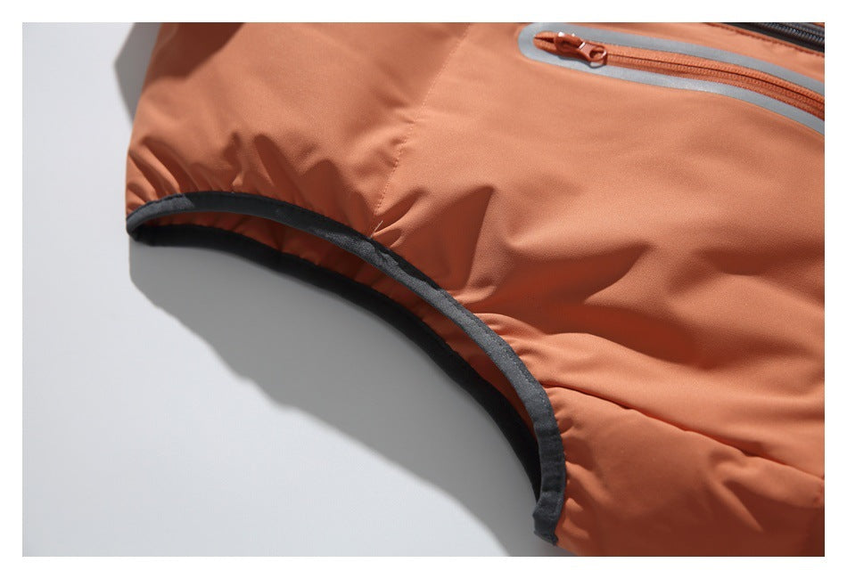 Close-up of the orange vest's armhole with dark binding and part of a gray-trimmed pocket.