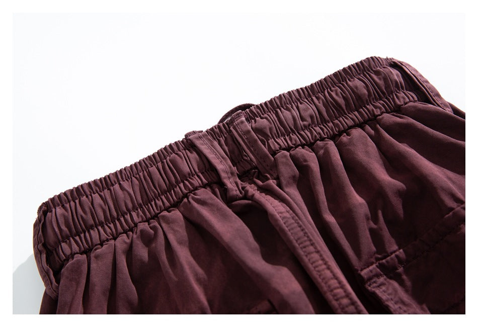 Close-up of the burgundy pants' gathered elastic waistband and center front seam.