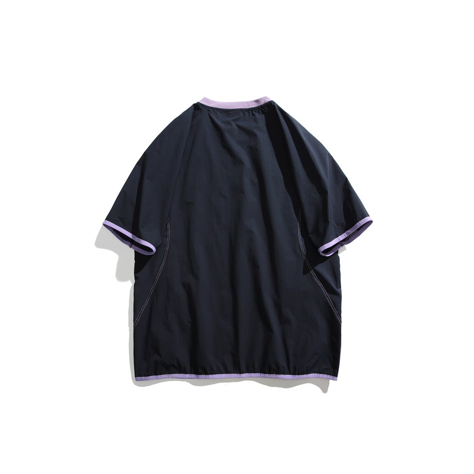 Back view of a plain oversized black short-sleeve shirt with lavender trim at the collar, cuffs, and hem.