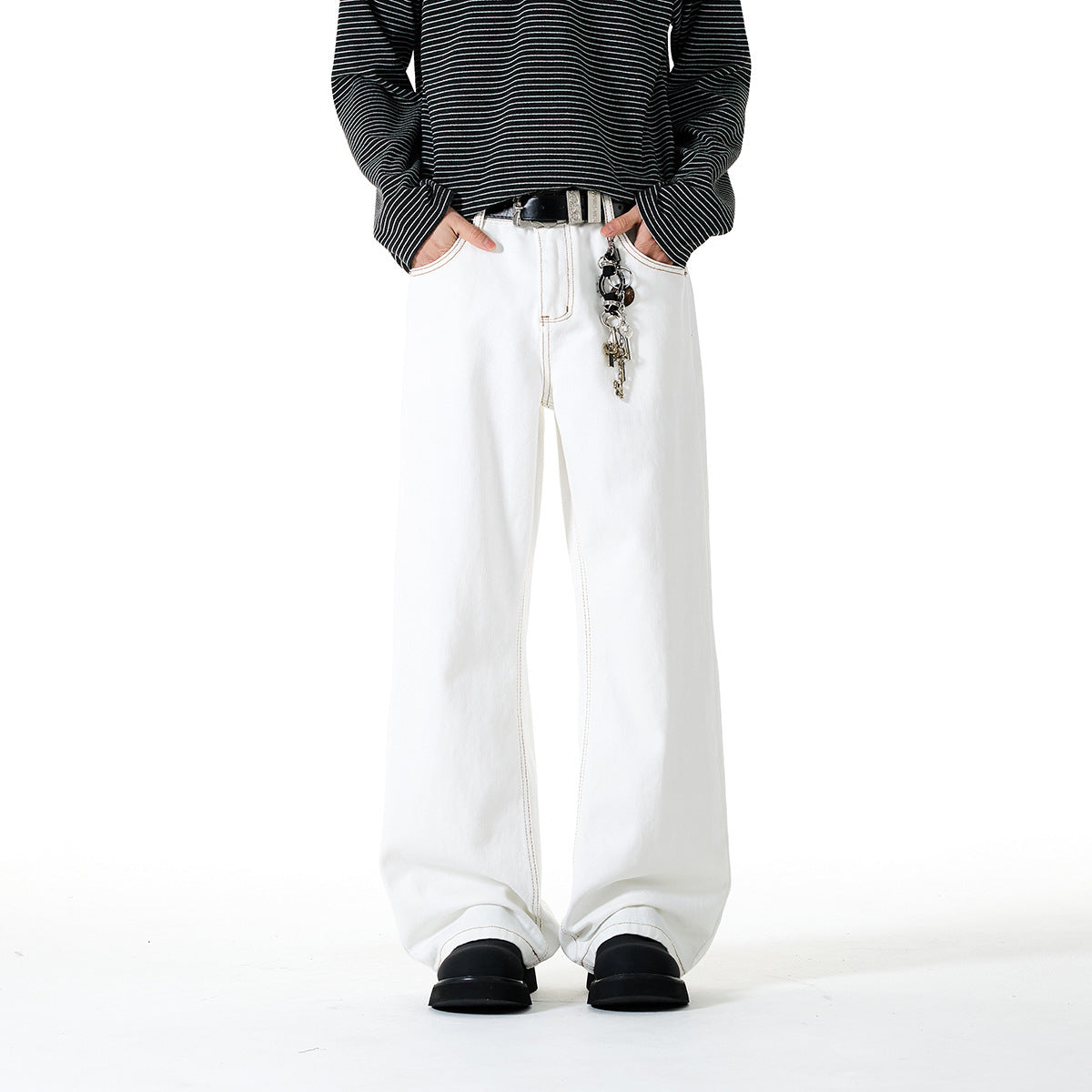 Front view of a model wearing white wide-leg pants with contrast stitching, a black striped top, and a belt with keychain.