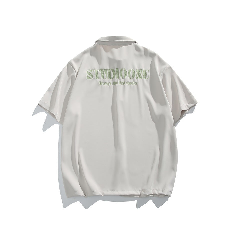 Back view of an off-white short-sleeve button-up shirt with pale green lettering across the upper back.