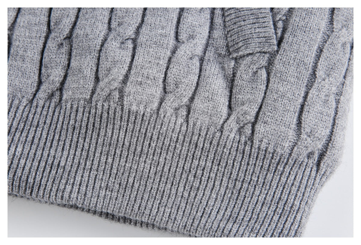 Close-up of the gray sweater's cable-knit pattern and wide ribbed hem.