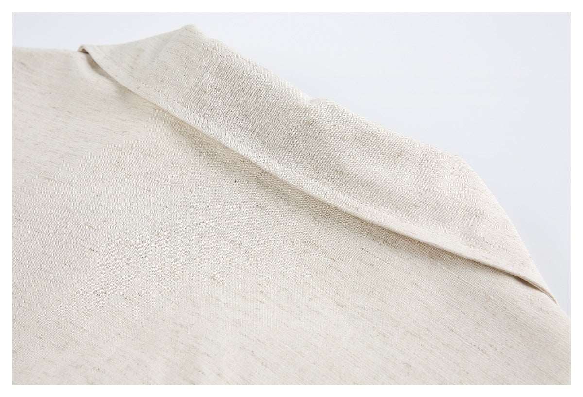 Close-up of light beige, subtly speckled fabric with a wide folded edge.