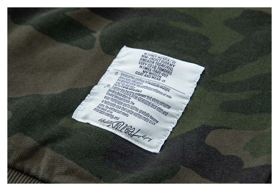 Close-up of a white text label sewn onto green camouflage fabric.