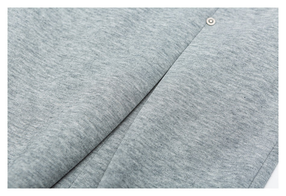 Close-up of heather gray garment fabric with a diagonal seam and small pale button.