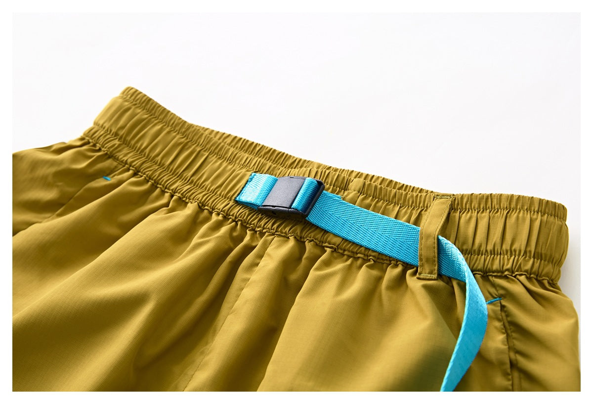 Close-up of the mustard shorts' elastic waistband and bright blue adjustable belt with a black buckle.