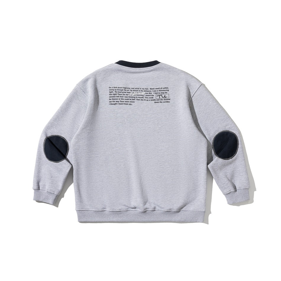 Back view of a light gray crew-neck sweatshirt with navy collar, navy elbow patches and a small block of printed text