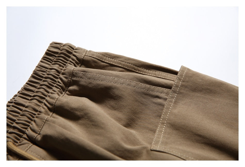 Brown pants waistband and a large rectangular side patch pocket shown in close-up.
