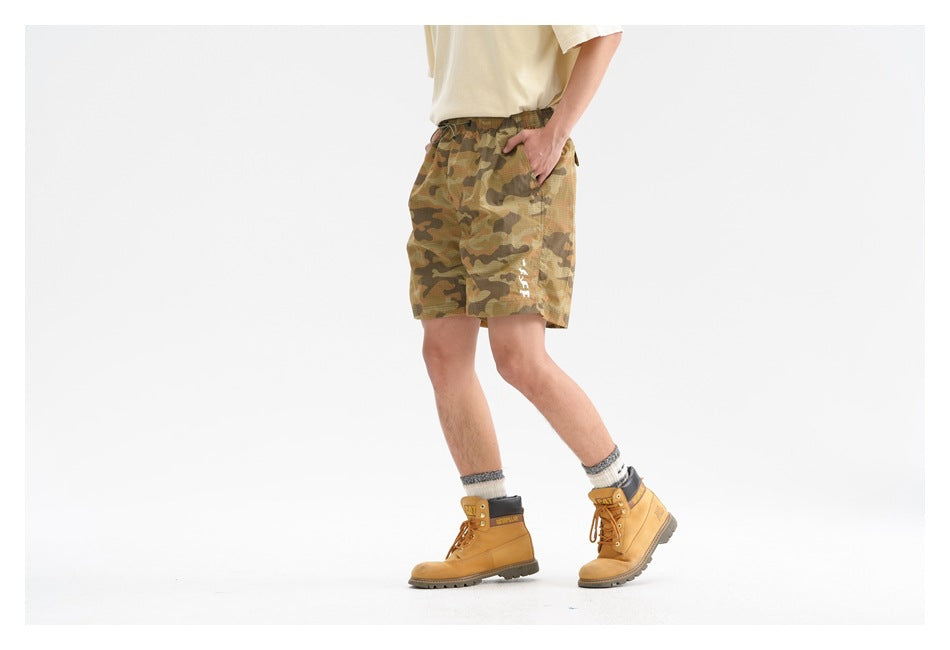 Model wearing olive and brown camouflage drawstring shorts, shown at a three-quarter angle.