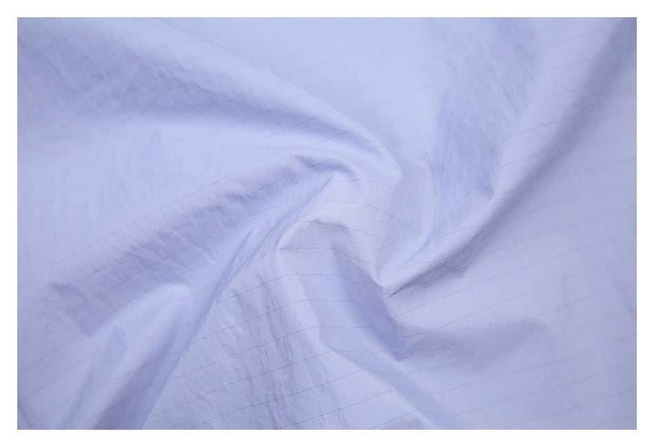 Close-up of lavender fabric with a subtle grid pattern and soft folds.