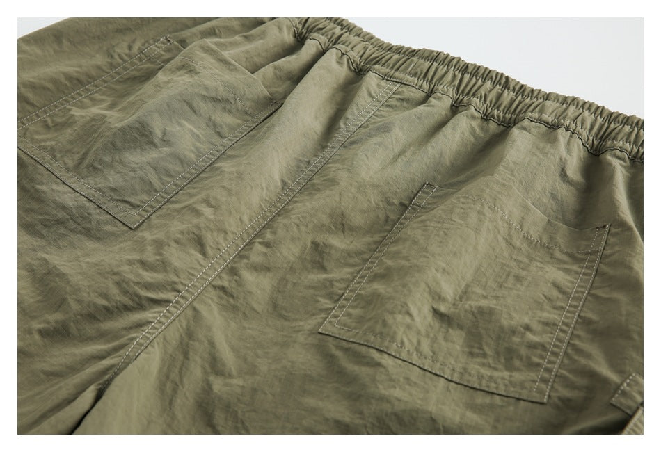 Olive shorts detail showing an elastic waistband and multiple stitched patch pockets.