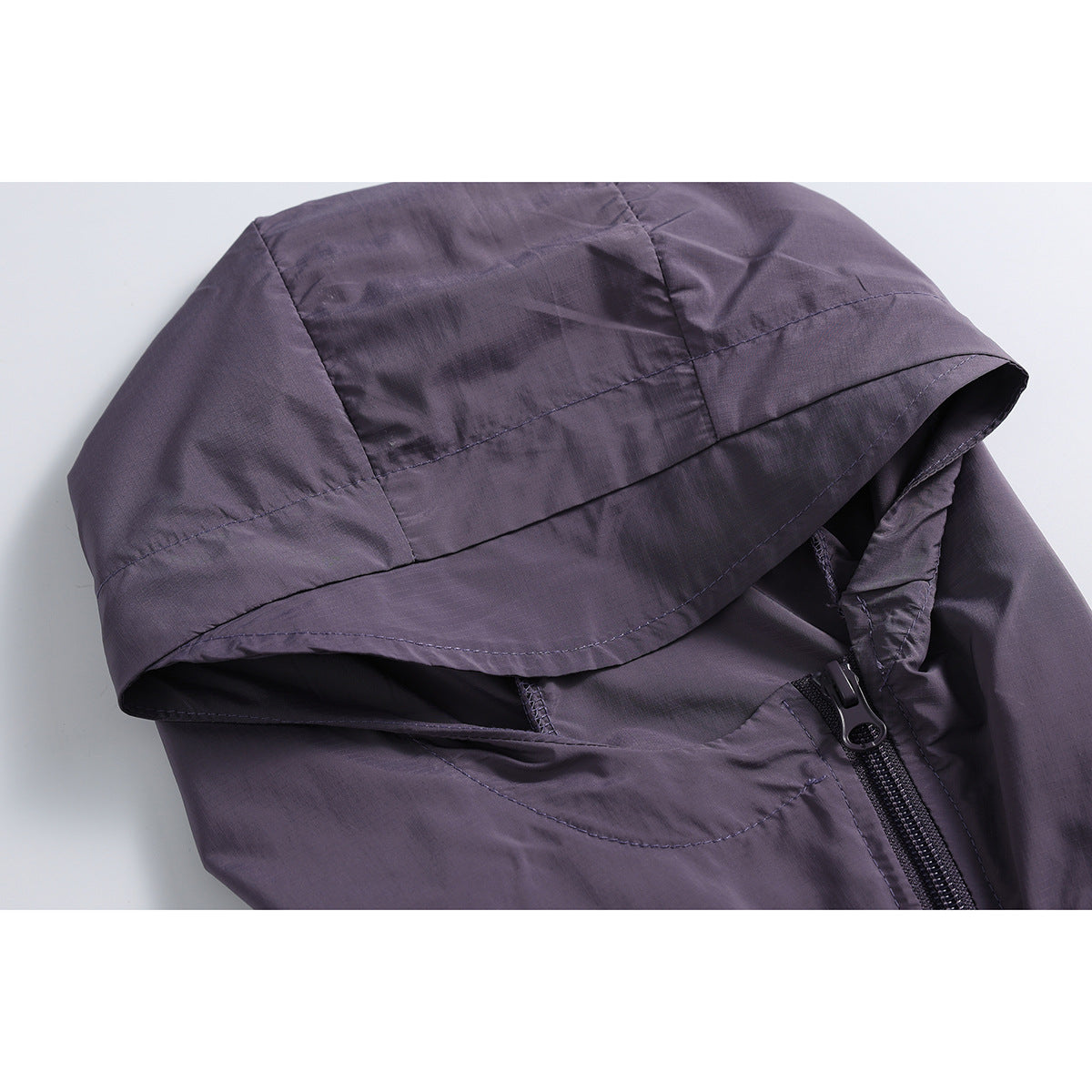 Close-up of a dark purple hooded jacket showing the paneled hood and front zipper.