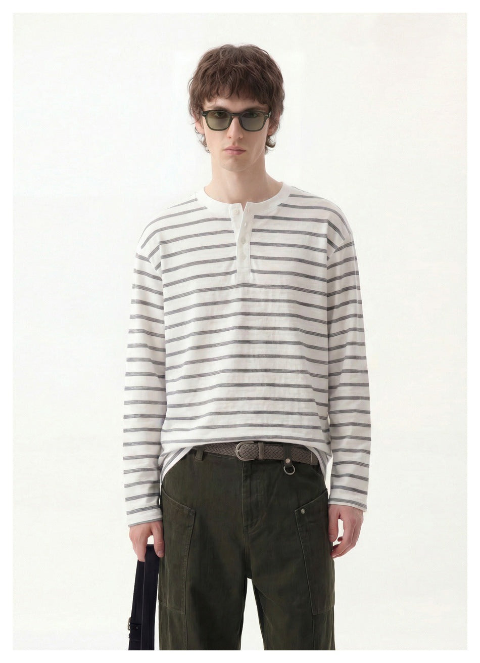 Close-up of a model wearing a white long-sleeve henley with gray stripes and olive pants with a braided belt