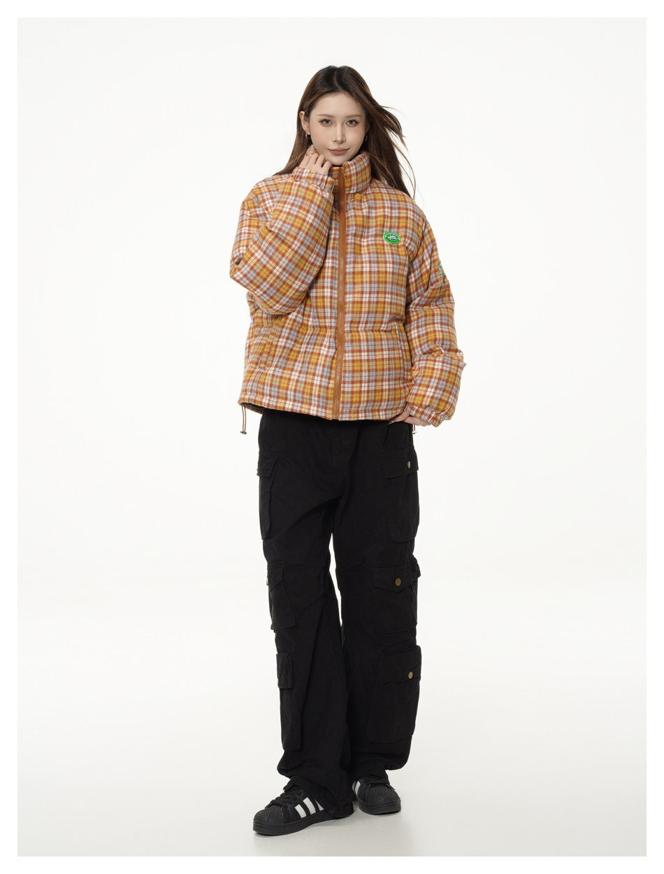 Full-length view of a model in the orange plaid puffer-style jacket with black cargo pants and black sneakers
