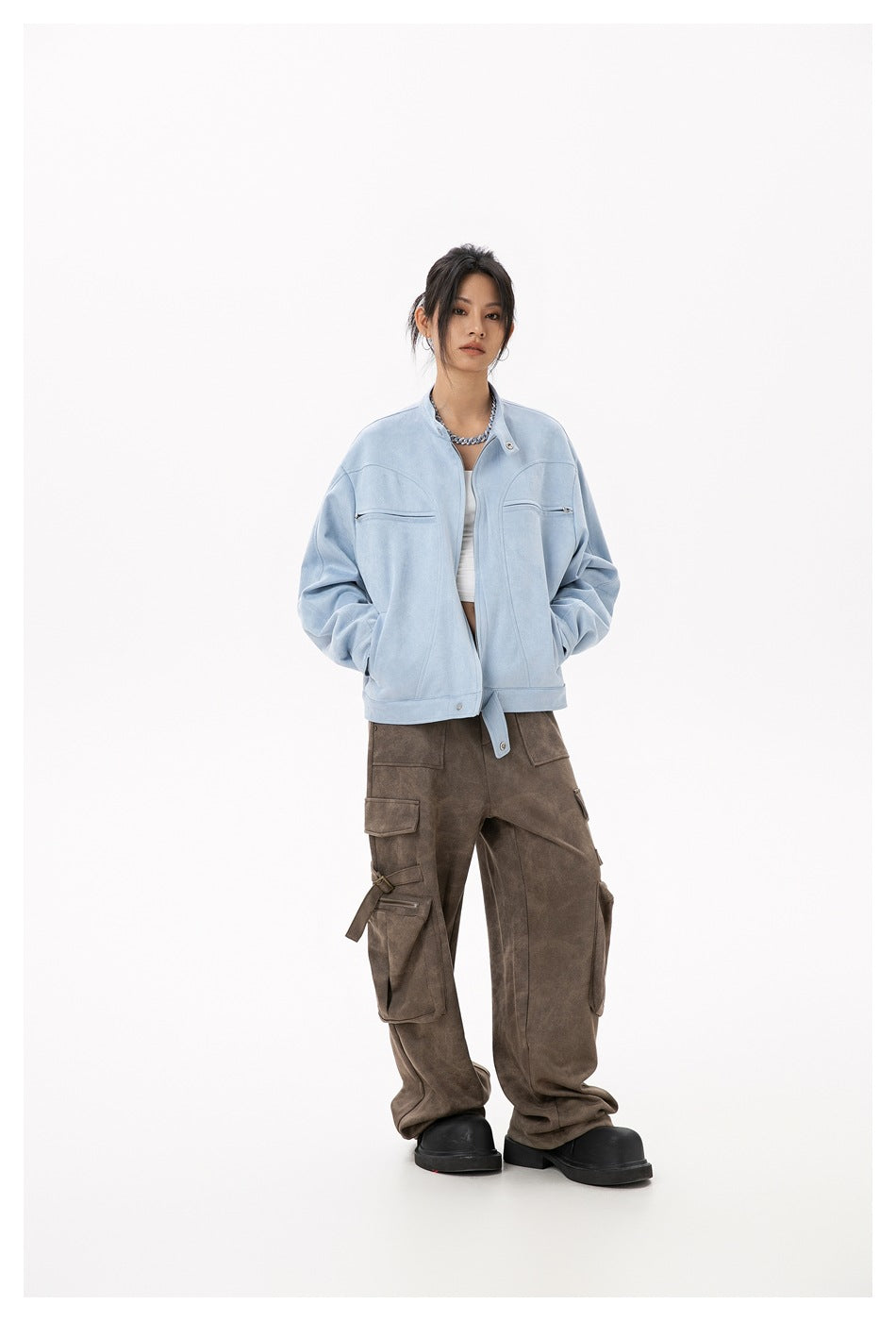 Front view of a model wearing a light blue zip-front jacket with brown cargo pants and black platform shoes.