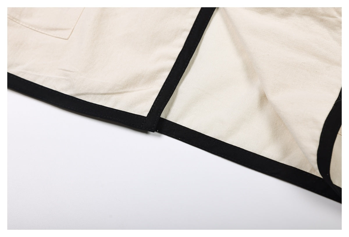 Close-up of the cream garment's hem and seam, finished with black binding.