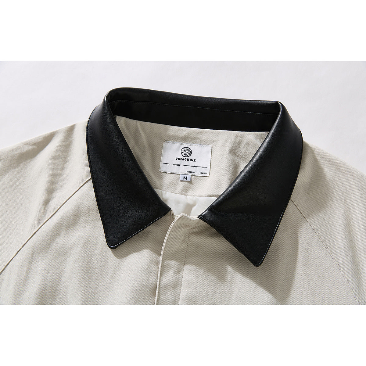 Close-up of an ivory jacket's wide black pointed collar, front placket, and inner neck label.