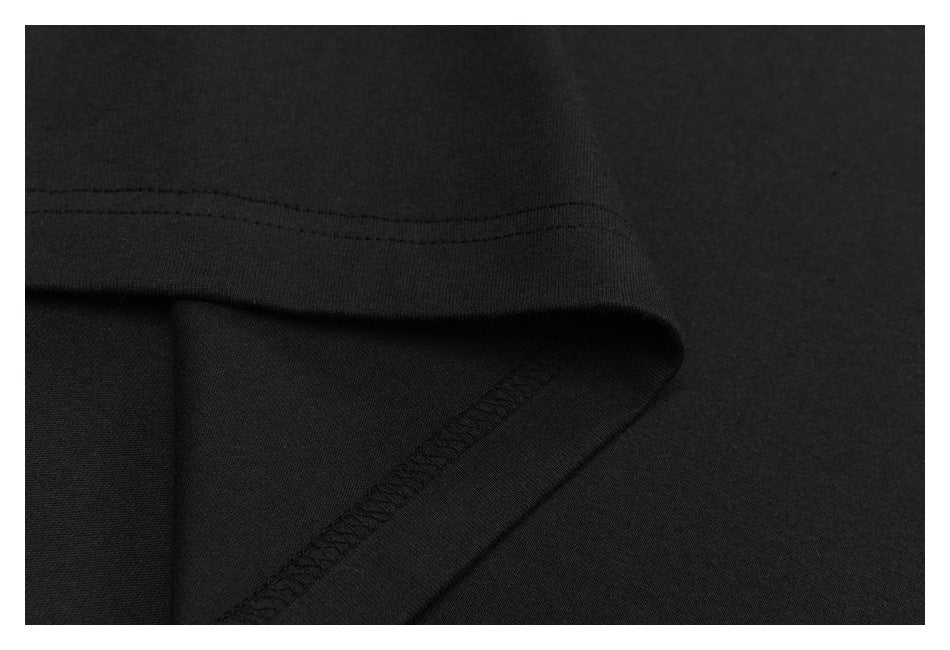 Close-up of a black garment hem with double stitching and an overlocked seam.