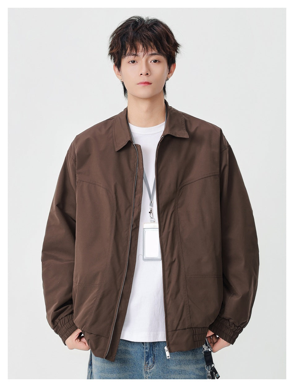 Front view of a model wearing a brown collared zip jacket with elastic cuffs and hem over a white shirt.