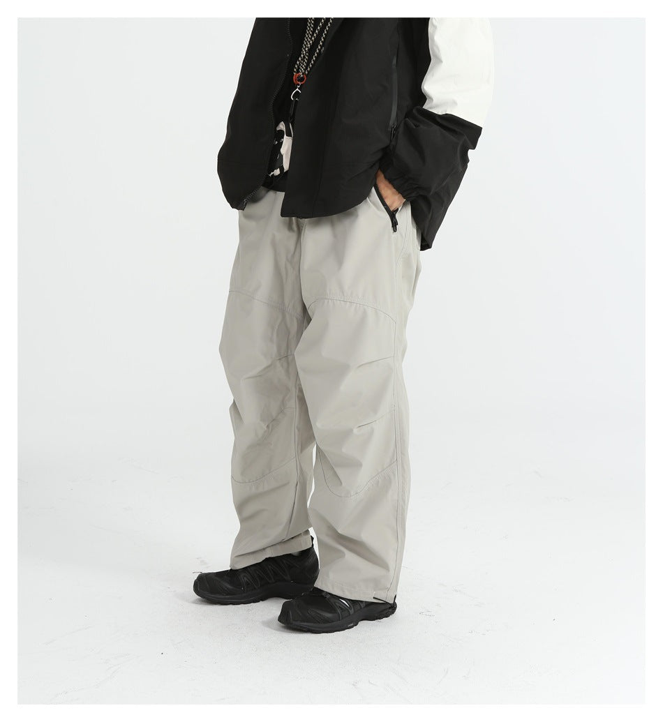 Model wearing light gray loose pants with a hand in the zippered pocket, black sneakers, side three-quarter view