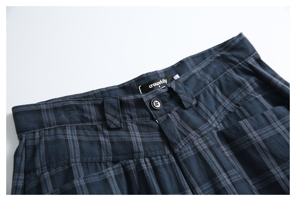 Close-up of navy plaid shorts showing the waistband, button, belt loops, and sewn-in brand label.