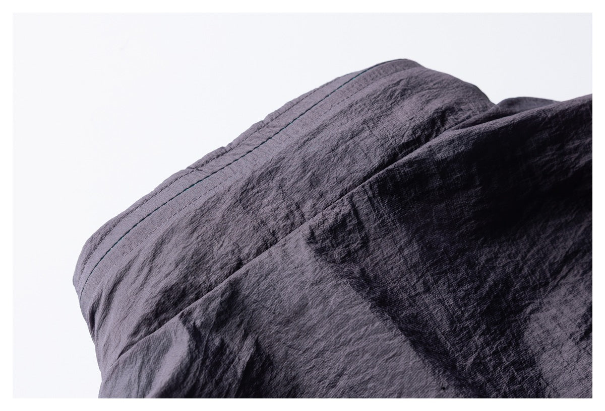 Close-up of a dark purple-gray garment seam with parallel stitching and a narrow contrasting stitch line.