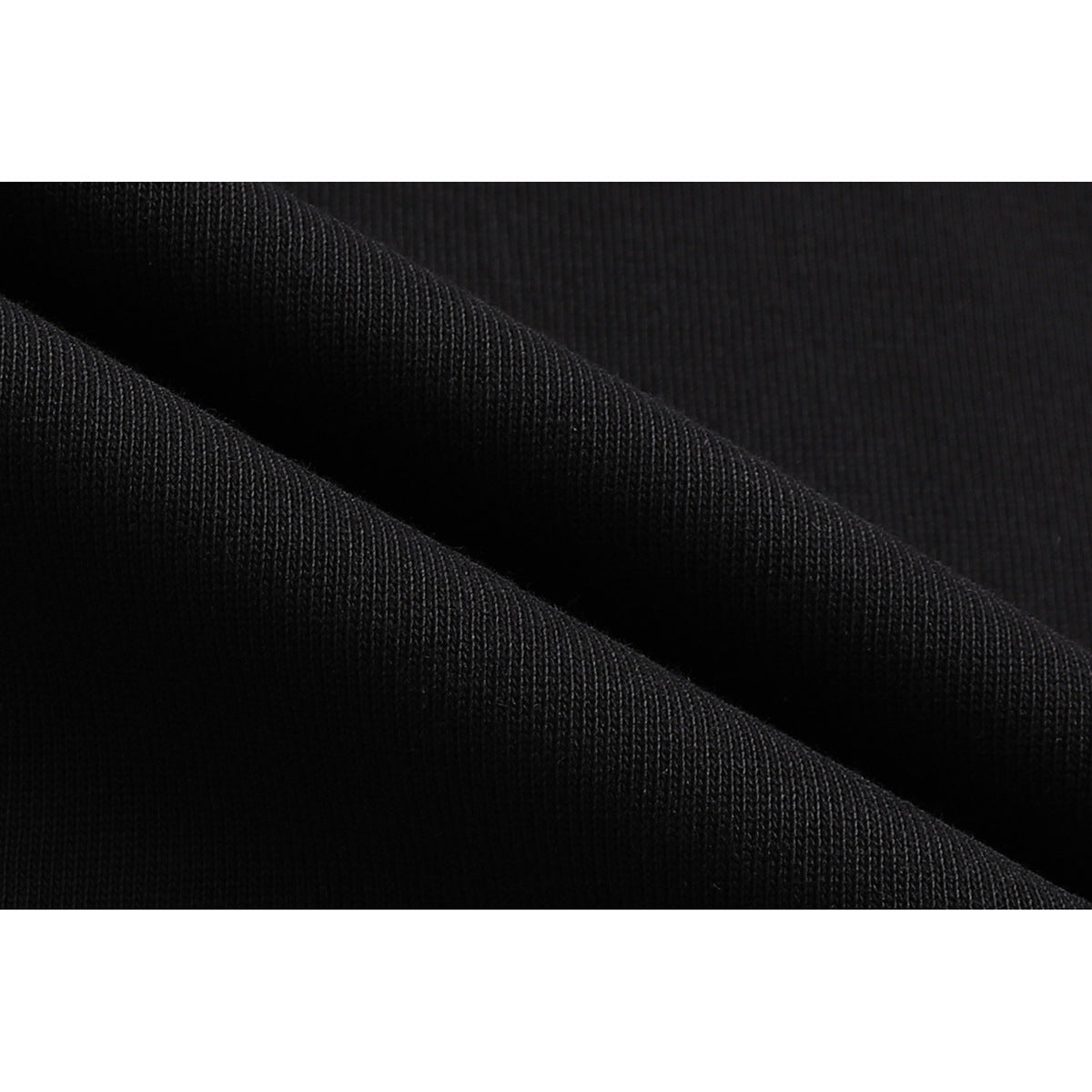 Macro view of black ribbed knit fabric folded into diagonal ridges.