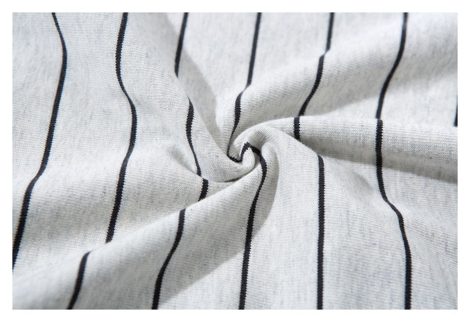 Close-up of light gray fabric with narrow black vertical stripes gathered into folds.