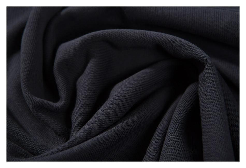 Close-up of dark charcoal fabric gathered into soft folds, showing its knit texture.
