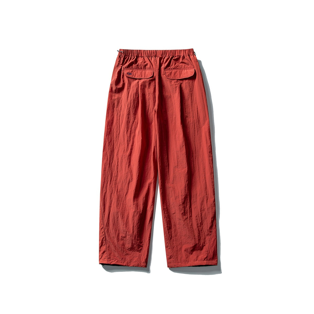 Coral red wide-leg pants with an elastic waist and two flap back pockets, shown from behind.