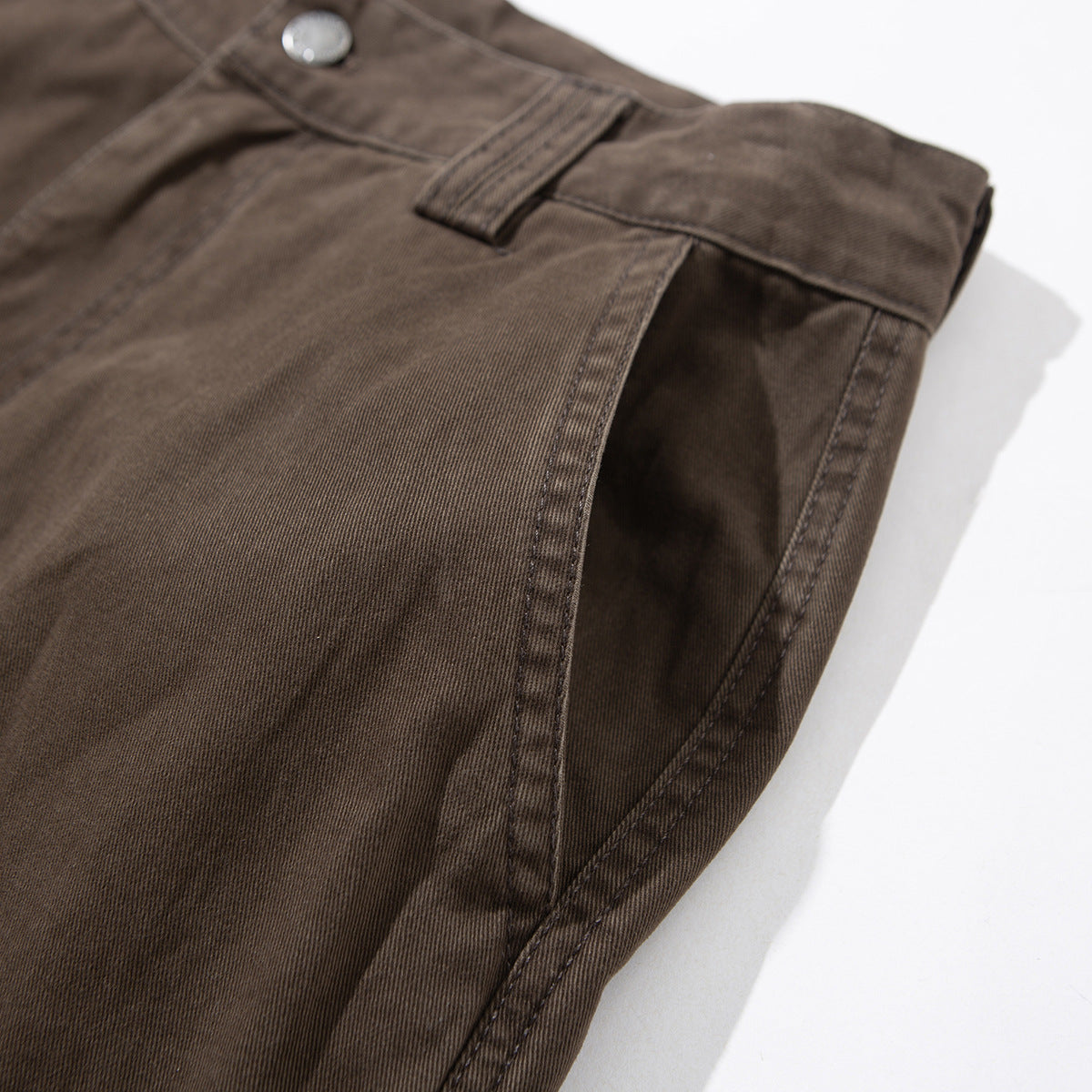 Angled close-up of brown cargo pants showing the waistband, belt loop, and side seam.