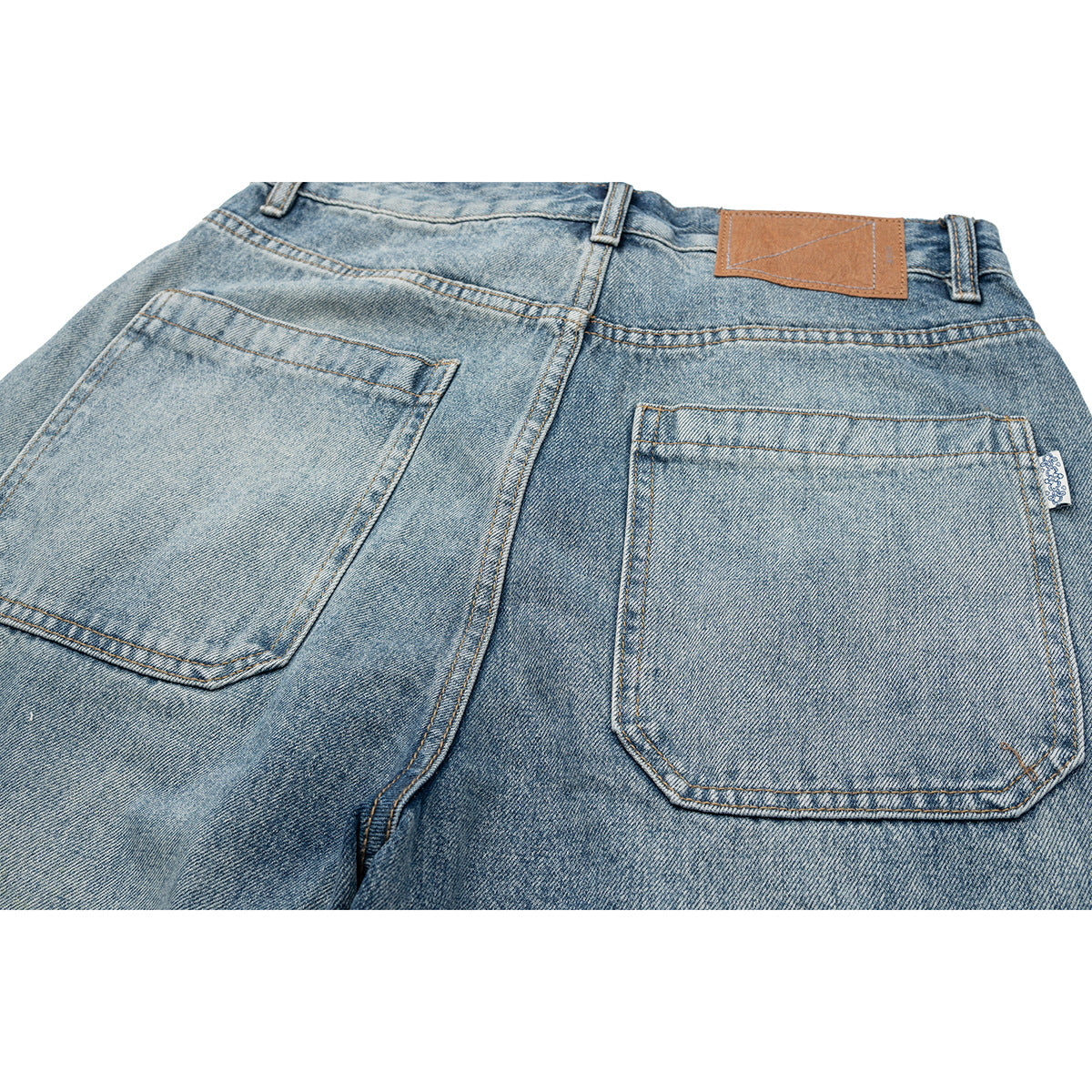 Close-up of the light blue jeans' back waistband, leather patch, and two stitched pockets.
