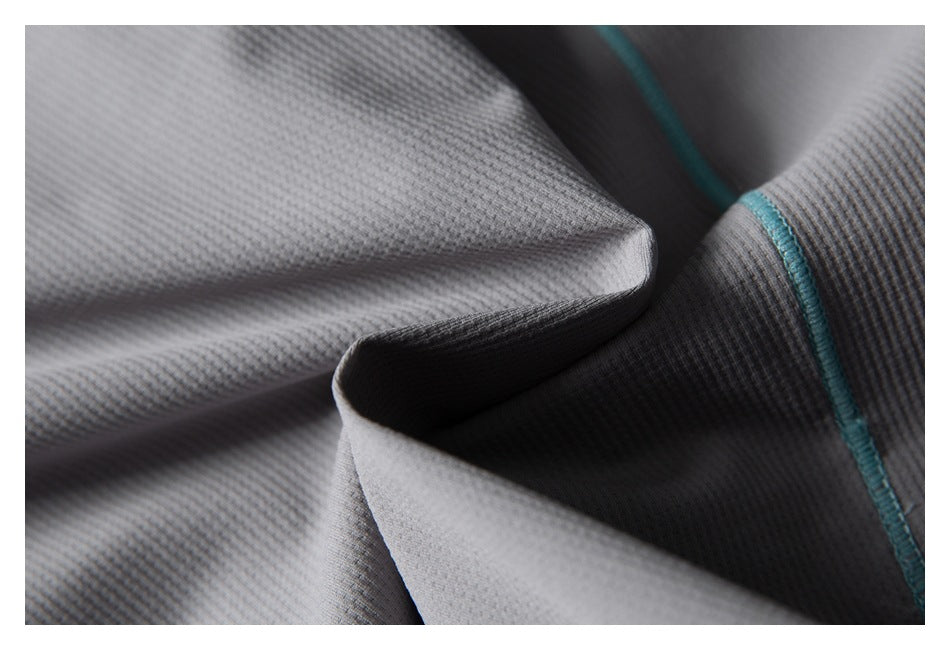 Macro view of gray textured garment fabric folded beside a turquoise stitched seam.