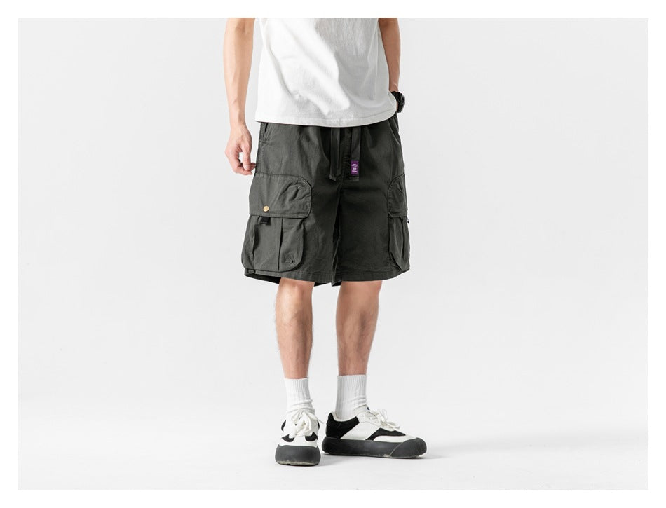 Model wearing dark charcoal cargo shorts with a drawstring waist and large flap pockets, shown from the front.