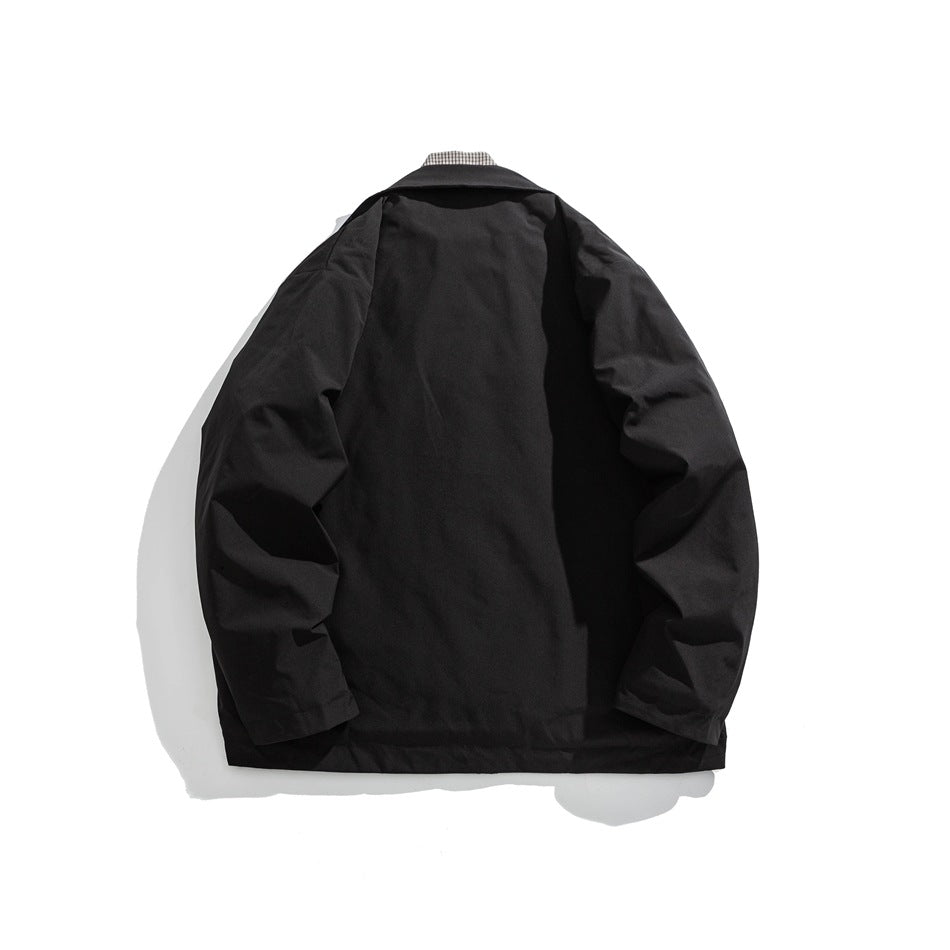 Back view of a black jacket laid flat against a white background, with a checked collar peeking out.