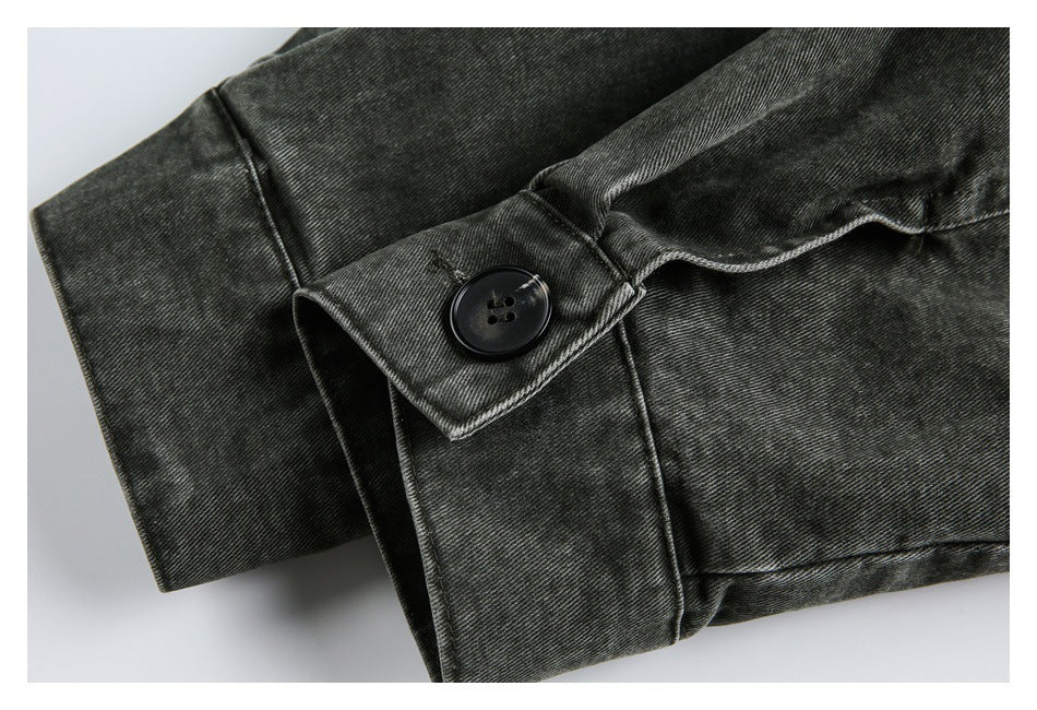 Close-up of a charcoal-black garment cuff with a large dark button and stitched flap.