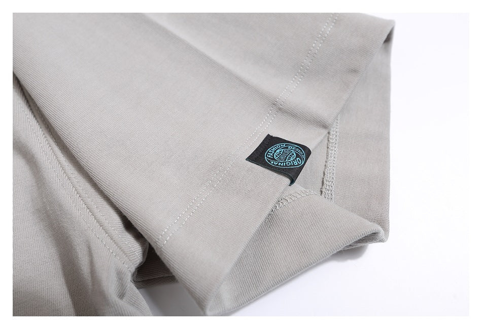 Close-up of a light gray sleeve cuff with a small black sewn-on tag.