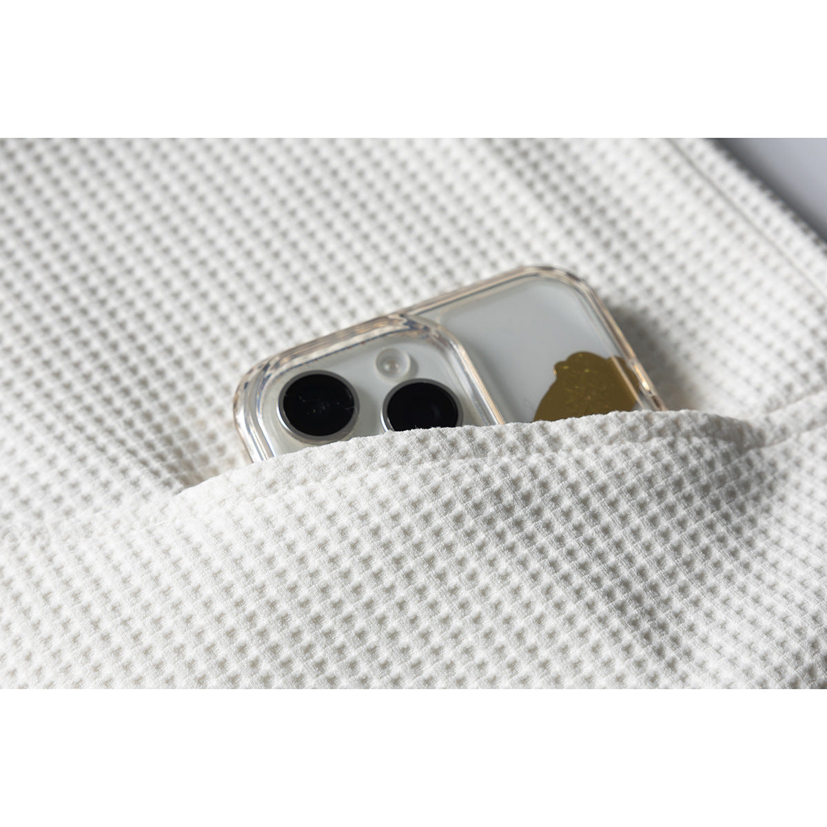 Close-up of an off-white textured garment pocket holding a smartphone.
