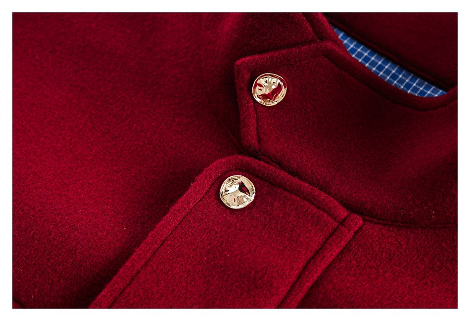 Close-up of two gold-tone buttons on a burgundy coat beside its collar and blue checked lining.
