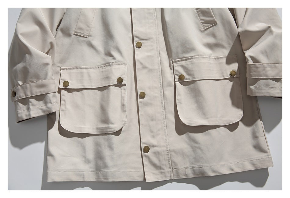 Cropped front view of a light beige jacket showing its button placket, flap pockets and cuff tabs.