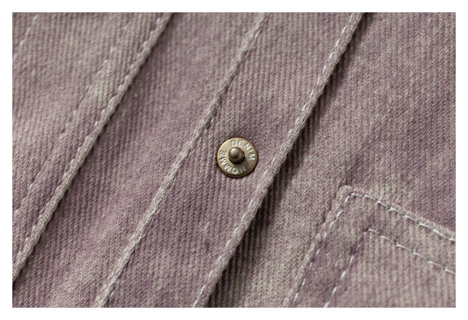 Close-up of a metal snap button, stitched placket, and textured mauve washed fabric.